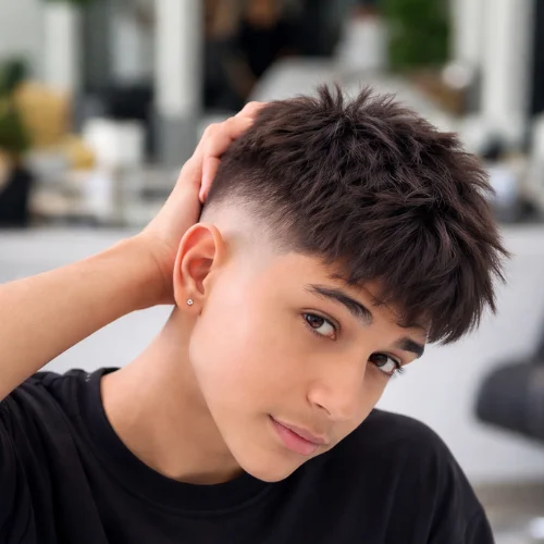 A trendy textured french crop mid fade with blended sides and a messy textured top, creating a modern and stylish look for young men.