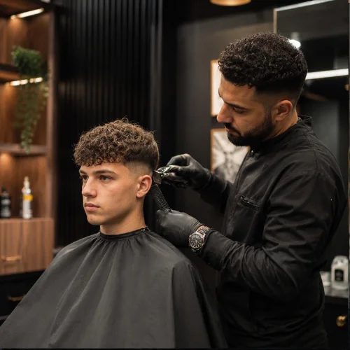 Barber cutting a Curly French Crop haircut in a modern barbershop